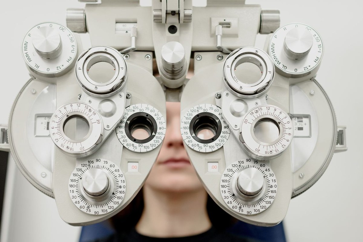 Close-up of a phoropter eye-exam device with a patient looking through the lens apertures